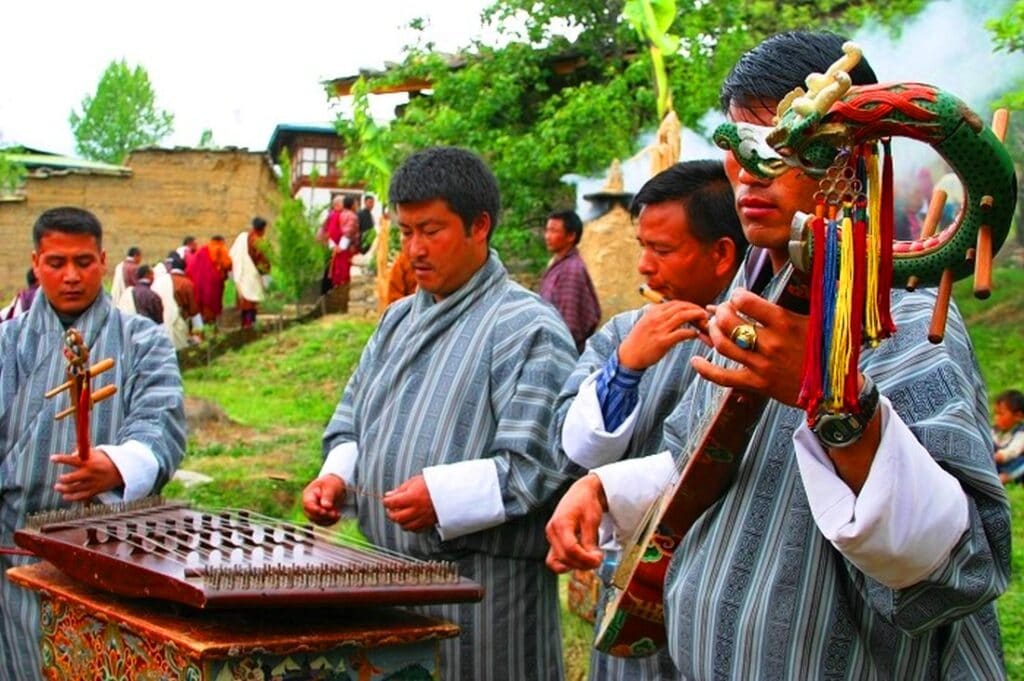 Männer in traditionellen Kleidern und Musikinstrumente in der Hand - Bhutan Reisen