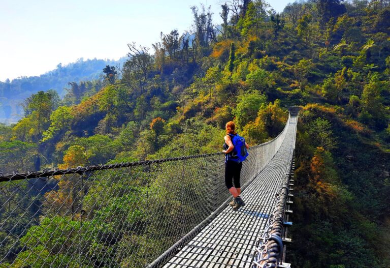 Trekkerin über eine Hängebrücke in Nepal, in der Annapurna Region