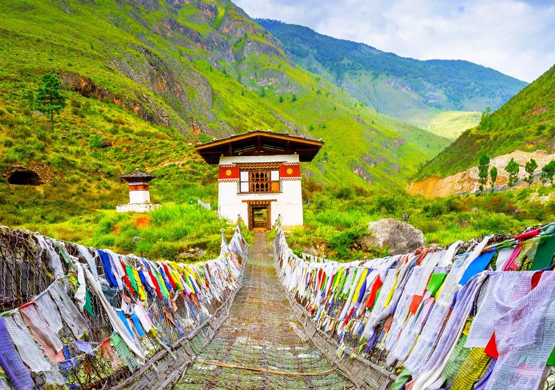 Brücke in Bhutan mit Gebetsfahnen und Stupa